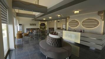 A modern hotel lobby with a curved seating area, a reception desk, and a large mirror.