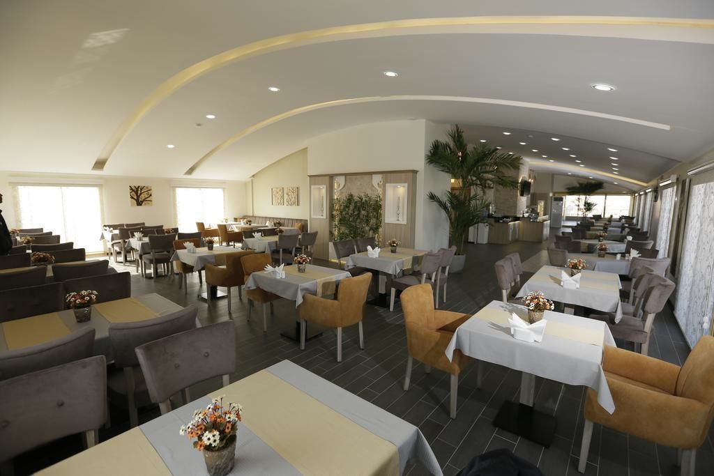 A spacious restaurant with multiple tables and chairs, a curved ceiling, and large windows allowing natural light.