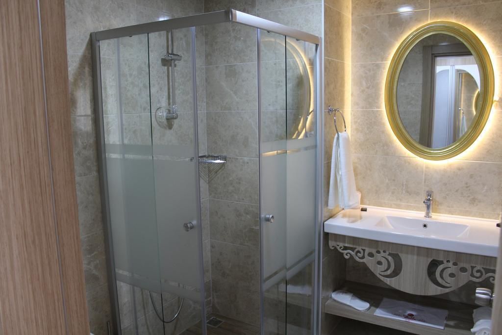 Un baño moderno con ducha envuelta en vidrio, tocador con espejo y lavamanos decorativo.