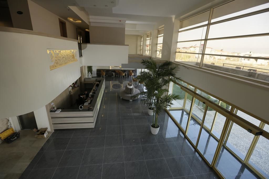 A spacious indoor area with a high ceiling, a staircase leading to an upper level, and large windows offering a view of the outside.