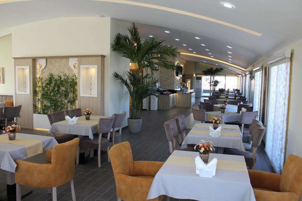 Un restaurante con mesas y sillas, algunas adornadas con flores. Se observan plantas y una barra de fondo.