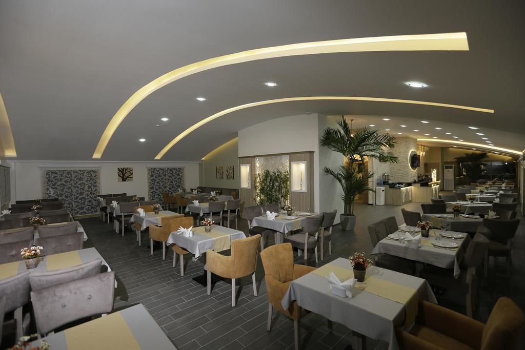 A restaurant with a modern interior, featuring curved ceiling lights, multiple dining tables, and chairs.
