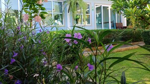 Un edificio moderno con amplios ventanales, un patio cubierto y abundante vegetación.