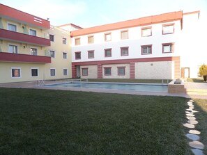 A multi-story building with a swimming pool and a well-maintained lawn.