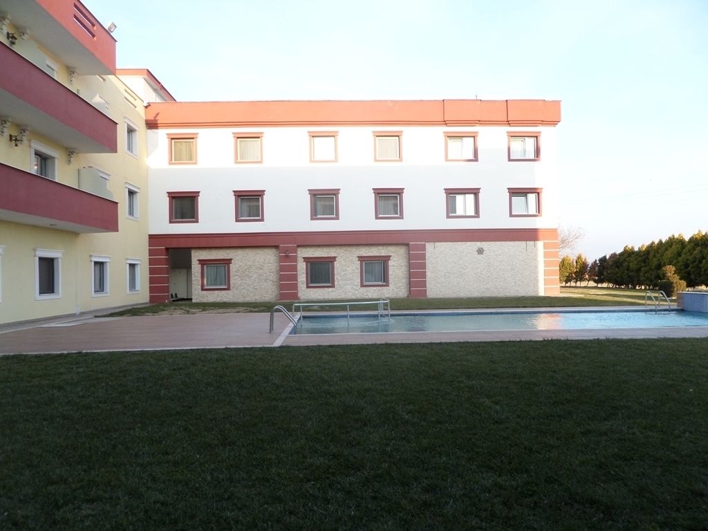 A multi-story building with a swimming pool in the foreground.