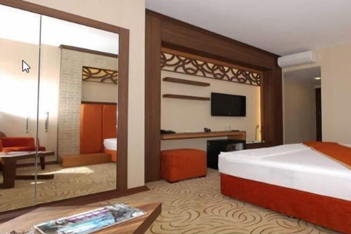 A hotel room with a bed, a TV, a desk, and a seating area.