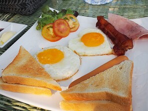A breakfast plate with eggs, bacon, tomatoes, and toast. - Baan Rachapuek (Phuket)