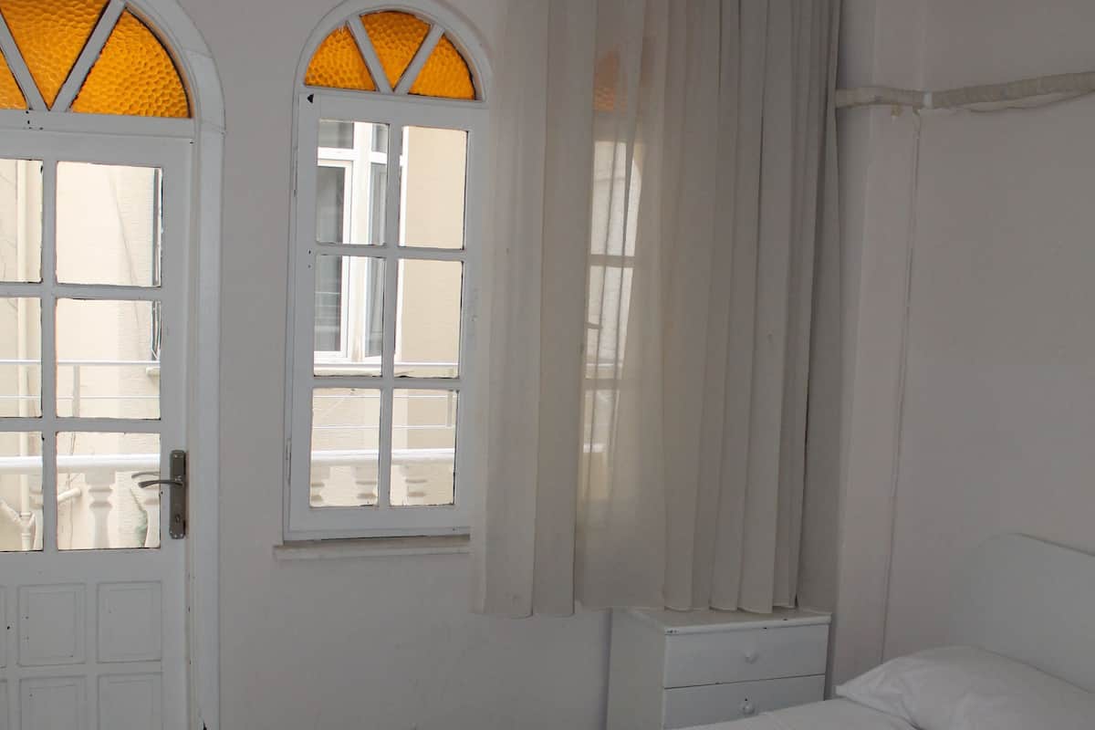A bedroom with a bed, a window with curtains, and a door.