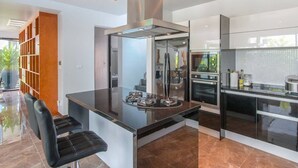 Une cuisine moderne dotée d’un îlot central, d’appareils électroménagers intégrés et d’un design épuré.
