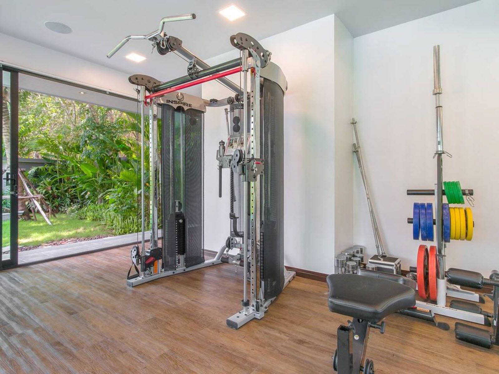A gym with a squat rack, bench, and various weights.