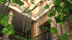 Un atrium à plusieurs niveaux, agrémenté de plantes suspendues et d’un escalier.