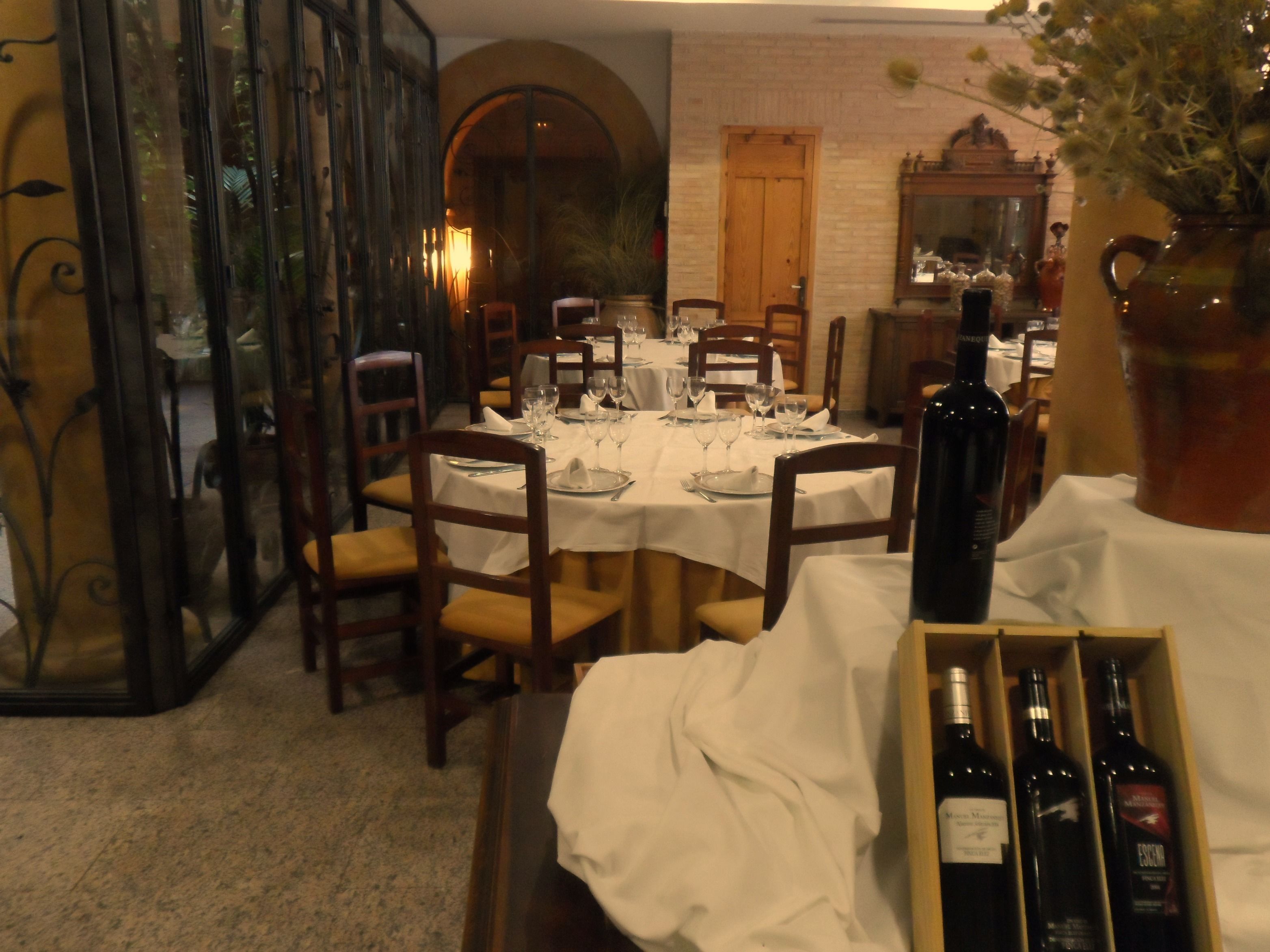 Un comedor con mesas dispuestas para una comida, una botella de vino y una caja de botellas de vino.