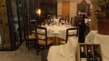 Un comedor con mesas dispuestas para una comida, una botella de vino y una caja de botellas de vino.