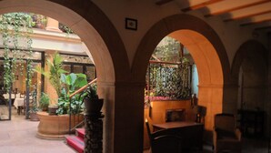 Un espace intérieur agrémenté d’arches, d’un escalier et de plantes en pot.