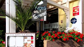 A hotel entrance with a sign reading "Les Bruyères en Terrasse" and a sign for "Bieri's Meteor".