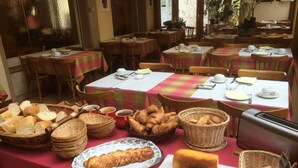 Ein Frühstücksbuffet mit verschiedenen Brotsorten, Gebäck und einem Toaster. Die Tische sind mit weißen Tischdecken und rot-grunchen Karottischläufern gedeckt.