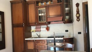 Une cuisine avec des meubles de rangement en bois, une cuisinière et une table à manger avec des chaises.