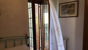 Une chambre à coucher avec un lit, une fenêtre avec des rideaux, un radiateur et un tableau encadré au mur.