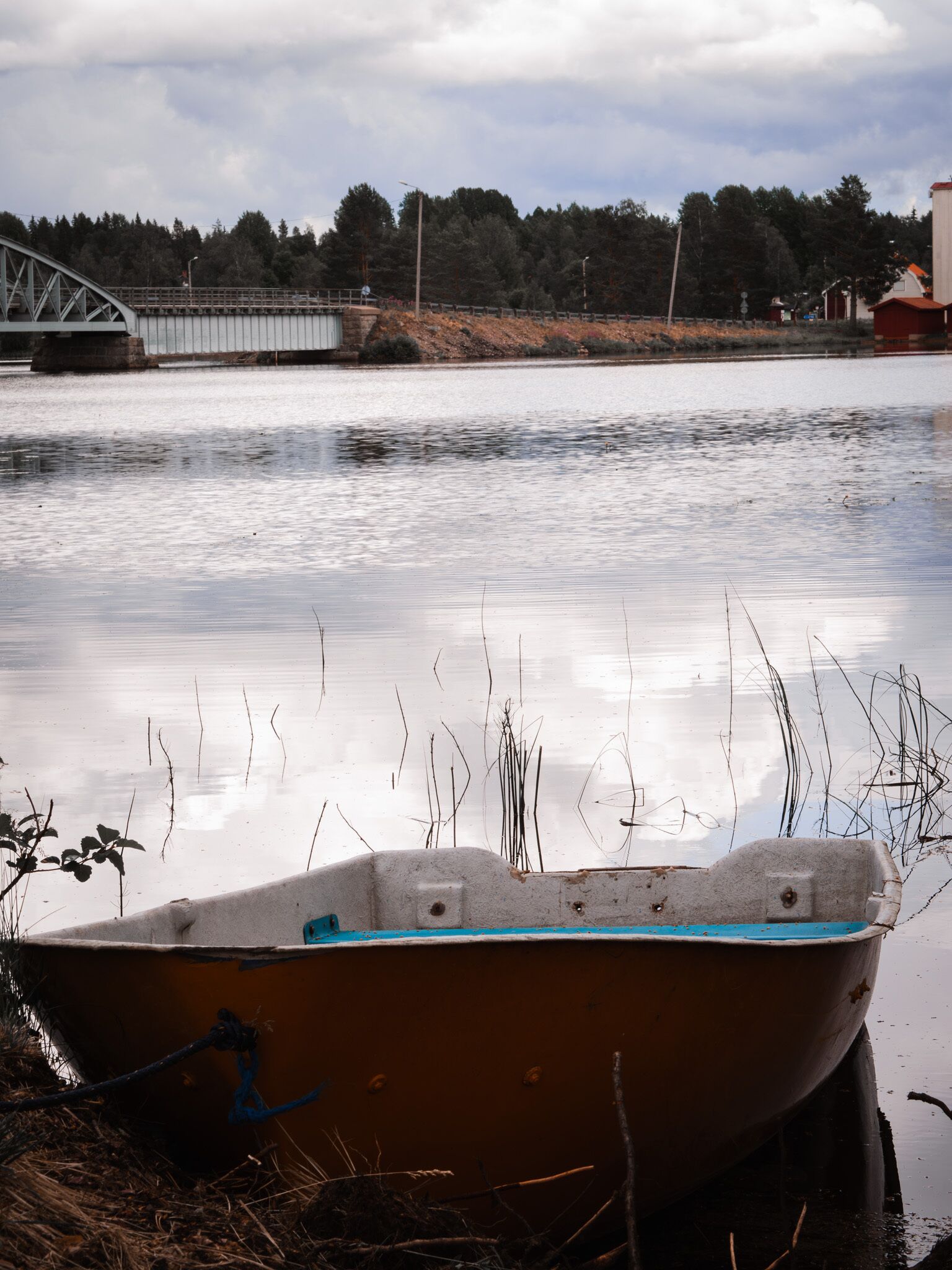 A boat tied to a dock with a bridge in the background.