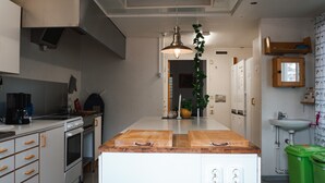 Una cocina moderna con una isla central, horno integrado y una lámpara colgante.