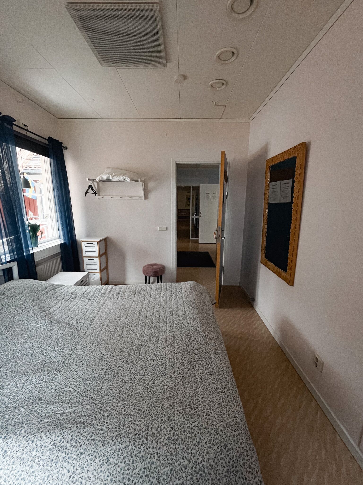 A bedroom with a large bed, a wardrobe, a mirror, and a door leading to another room.