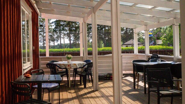 Un patio techado con suelo de madera, mesas y sillas.