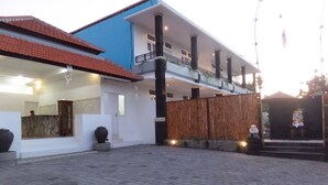 Un edificio de dos pisos con fachada azul y blanca, un balcón y una cerca de madera.