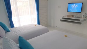 Habitación de hotel con dos camas, un televisor en la pared y un pequeño estante con cafetera.