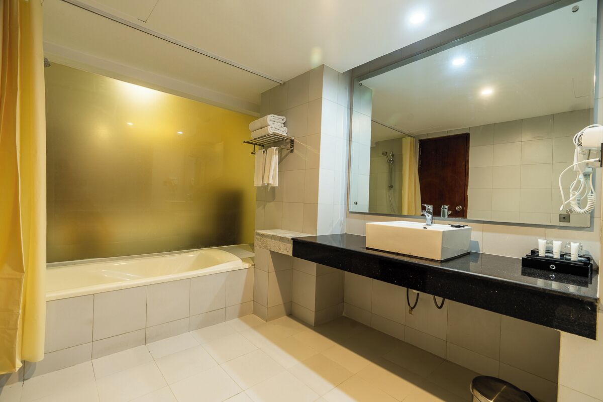 Een moderne badkamer met een bad, een wastafel, een spiegel en een haardroger.