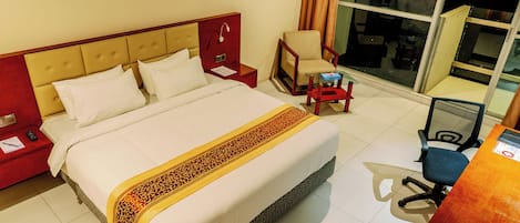 Une chambre d’hôtel avec un lit, une chaise, un bureau et une grande fenêtre donnant sur la ville.