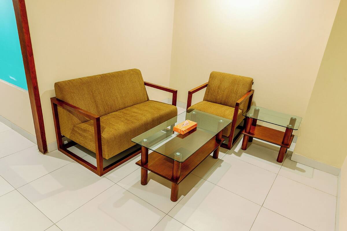 A room with a sofa, a chair, and a glass coffee table.