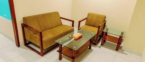 Una habitación con un sofá, una silla y una mesa de centro de vidrio.