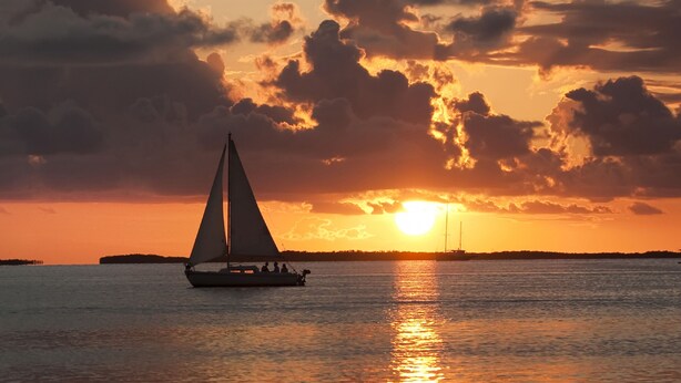 Un velero en aguas tranquilas durante el atardecer.