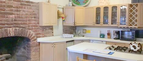 A kitchen with a brick fireplace, wooden cabinets, a microwave, and a coffee maker.