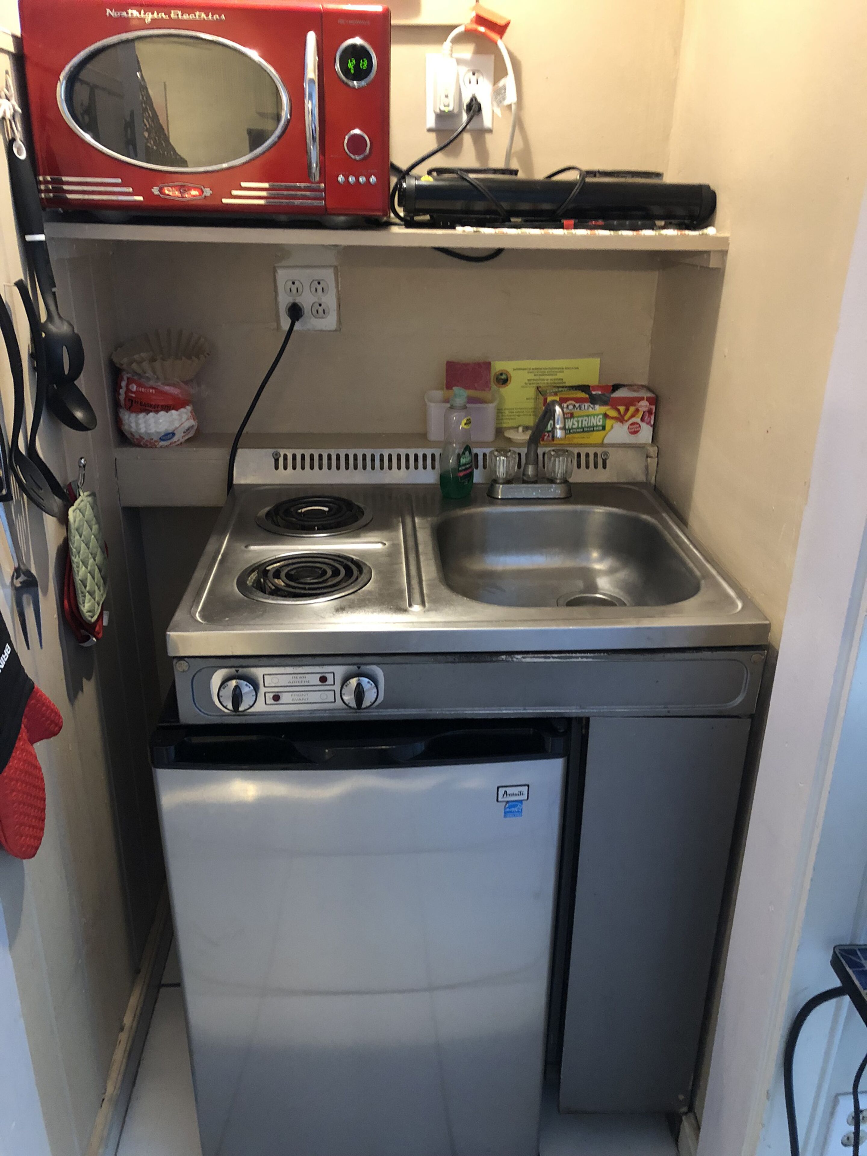 A compact kitchenette with a microwave, stove, and refrigerator.