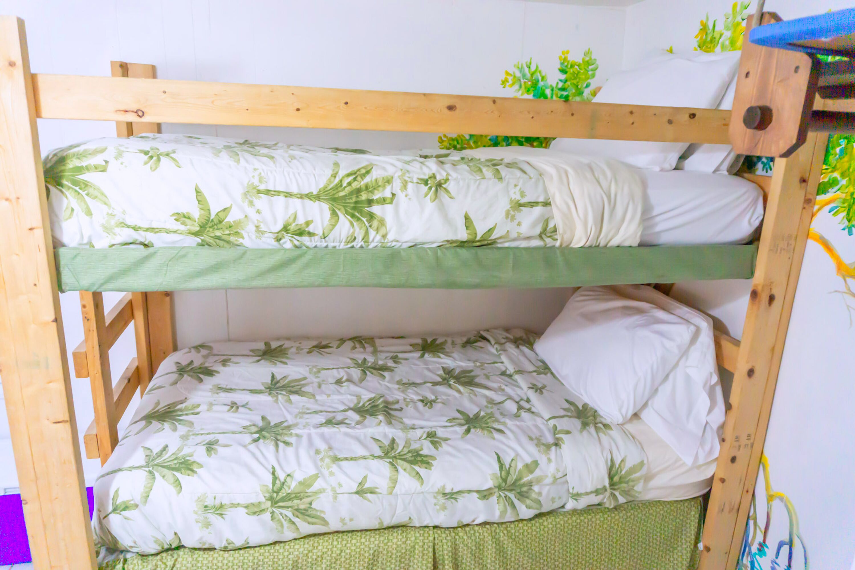 Ein Stockbett mit zwei Liegen, jede mit Kissen und einer grünen Decke.