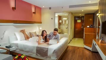 A modern hotel room with a bed, bedside table, and a bathroom visible through an open door.
