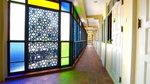 A corridor with a patterned glass partition and a tiled floor.