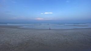 A beach with a wide sandy area and a person standing in the middle.