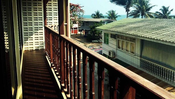 A balcony with a wooden railing overlooking a residential area with houses and palm trees.