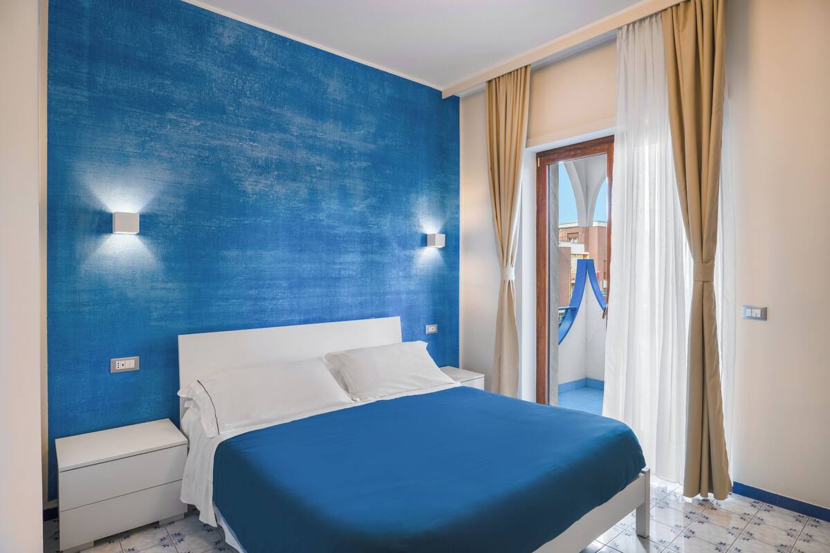A bedroom with a blue accent wall, a white bed, and a nightstand.