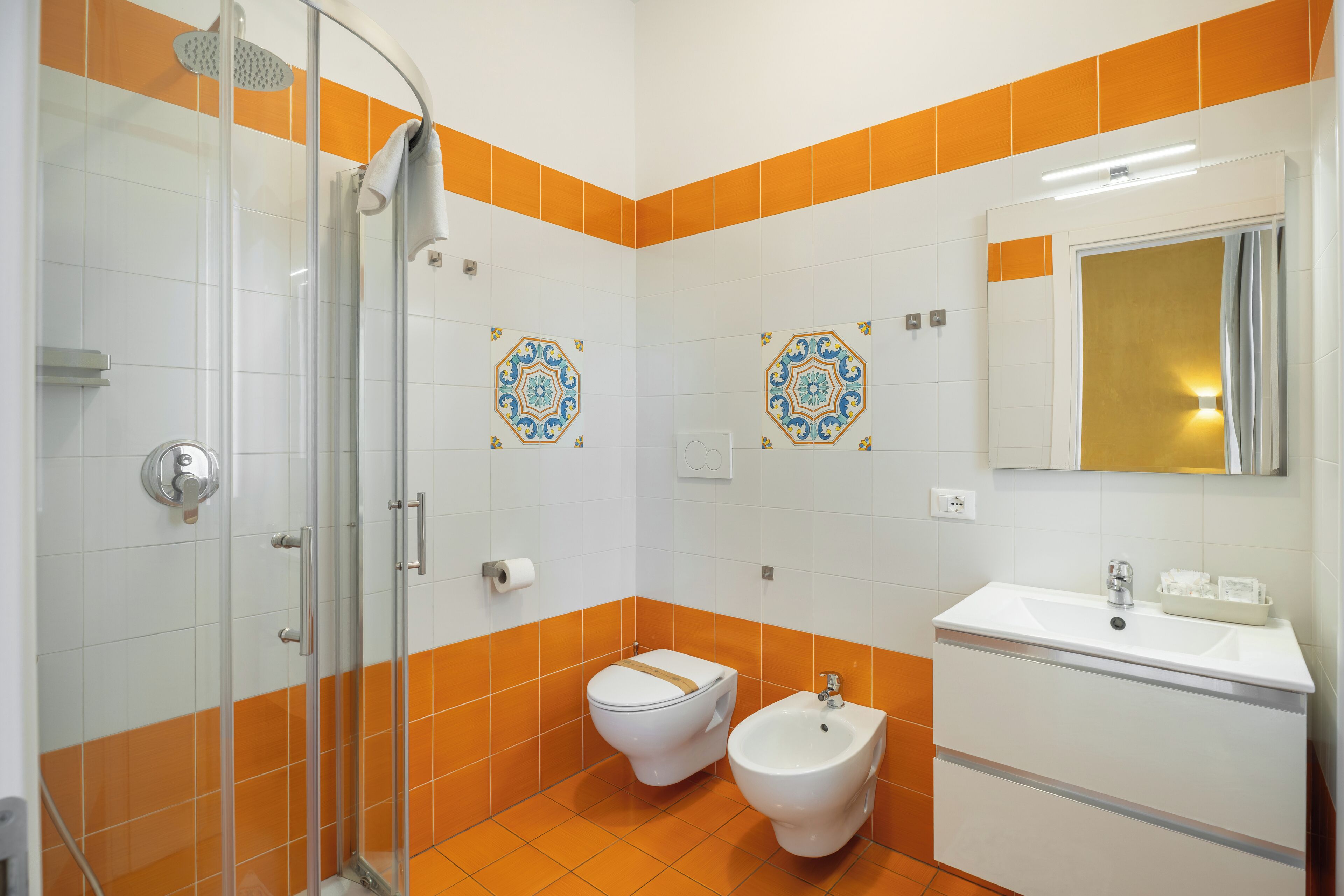 Une salle de bain avec une douche à parois de verre, des toilettes, un bidet et un lavabo avec un miroir au-dessus.