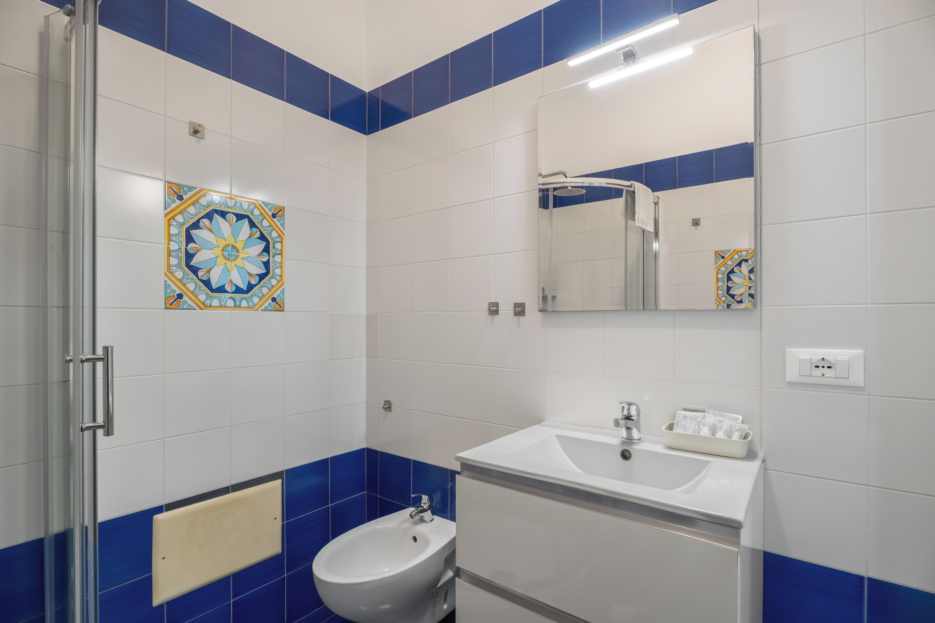 A bathroom with a white sink, a bidet, and a mirror.