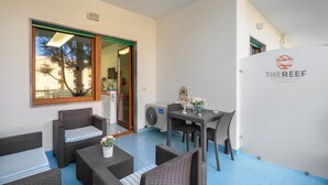 Un área de estar al aire libre con muebles de mimbre, una mesa y un jarrón decorativo.