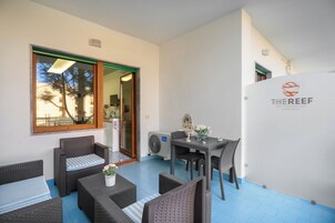Una zona esterna moderna con sedute in rattan, un tavolo e un vaso decorativo.