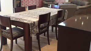 A dining area with a table set for six, surrounded by chairs. There is a sofa and a recliner in the background. - Villa La Fidèle (Aghir)