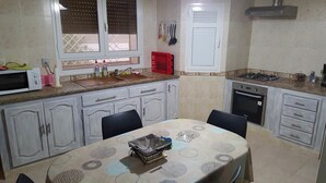 A compact kitchen with a dining area, featuring a microwave, sink, stove, and cabinets. - Villa La Fidèle (Aghir)