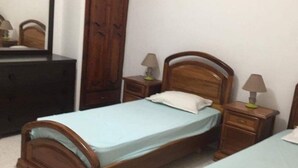 A bedroom with two wooden beds, a wardrobe, and a mirror. - Villa La Fidèle (Aghir)