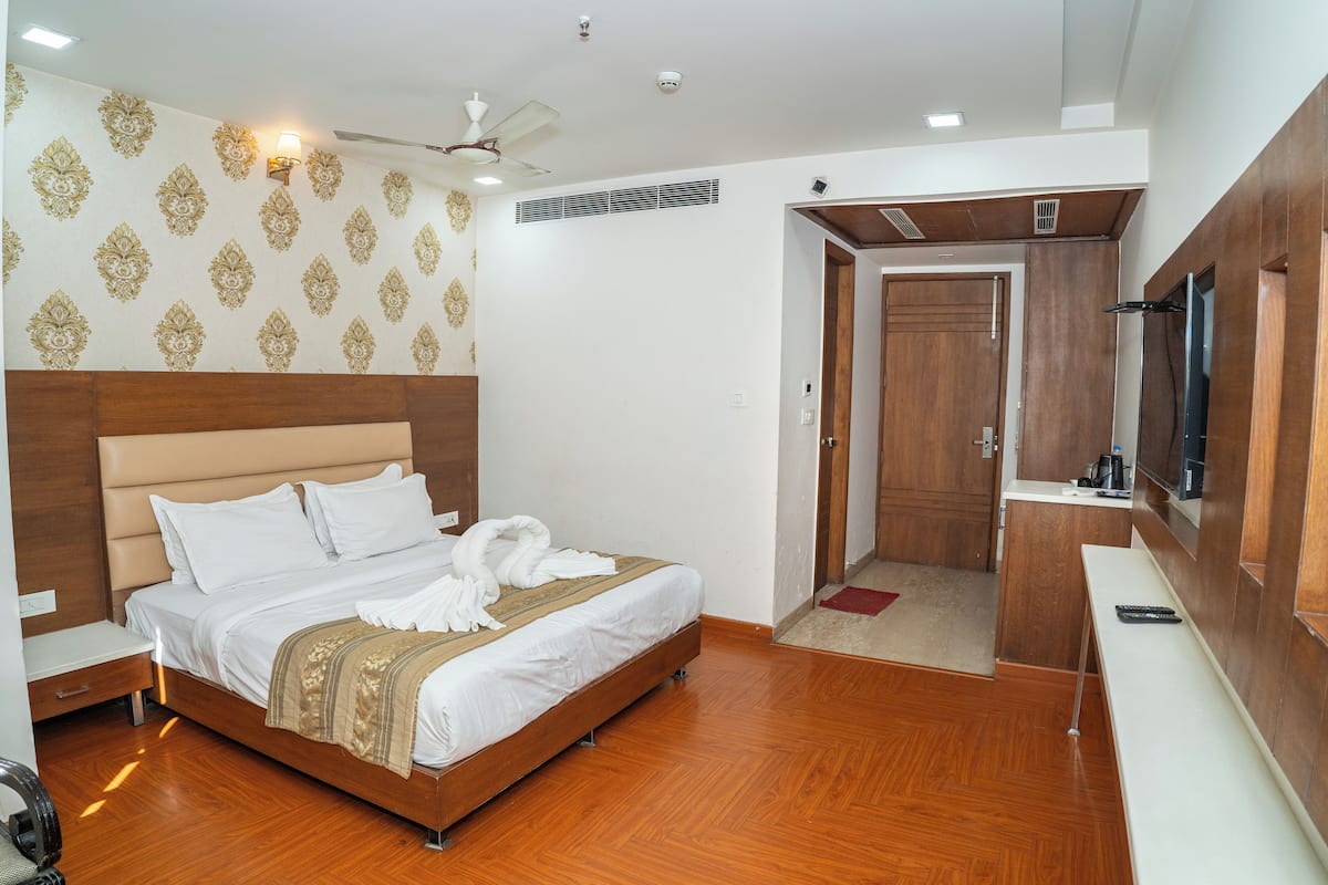 Habitación de hotel con cama, televisor, escritorio y zona de ducha.