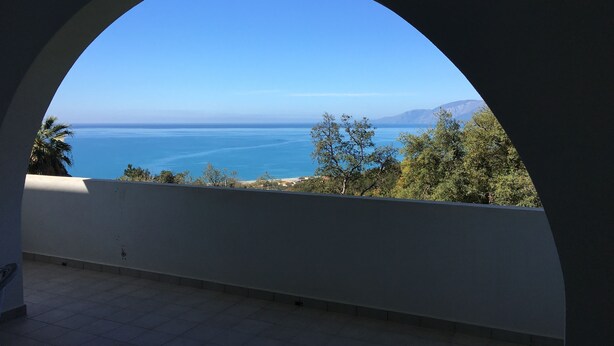 A room with a large arched window overlooking a coastal view. - La Bouganville (Vibonati)